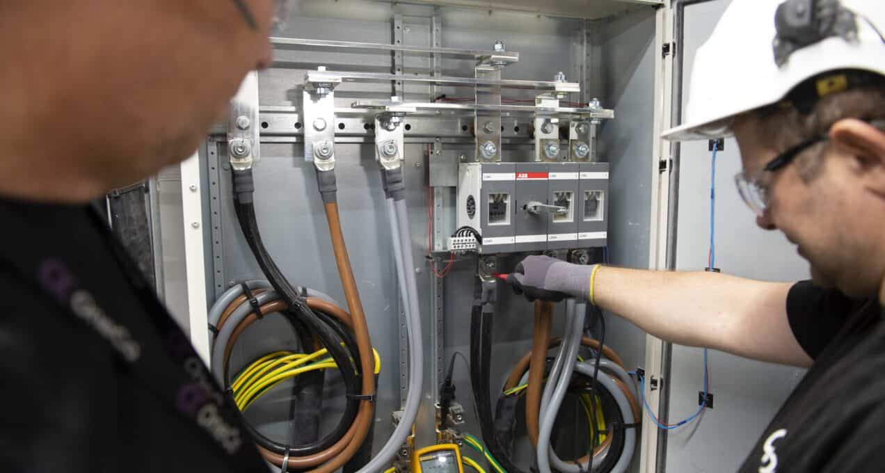 Two people are seen working on a professional level electric system.